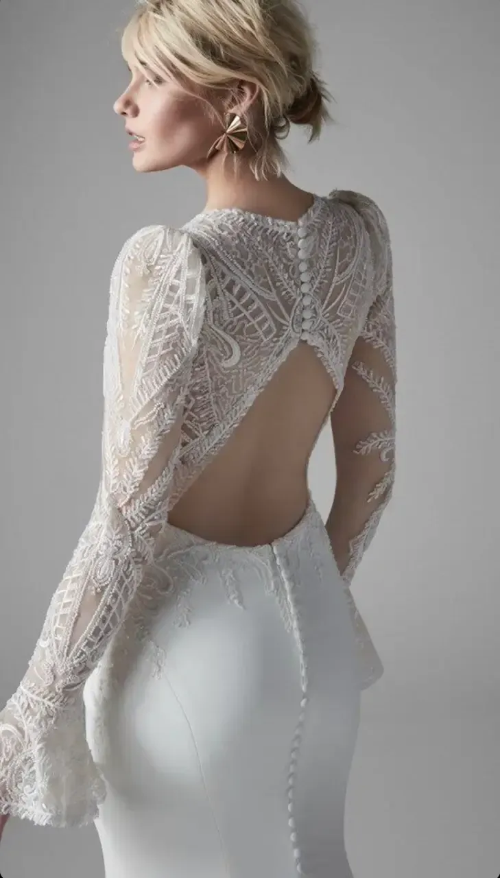 Woman in white wedding dress with lace sleeves and open back.