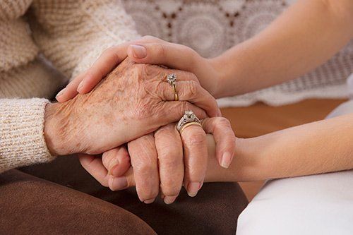 older woman and caretaker holding hands