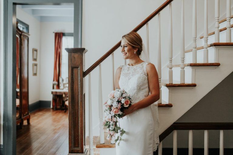 A bride is standing on a set of stairs holding a bouquet of flowers.