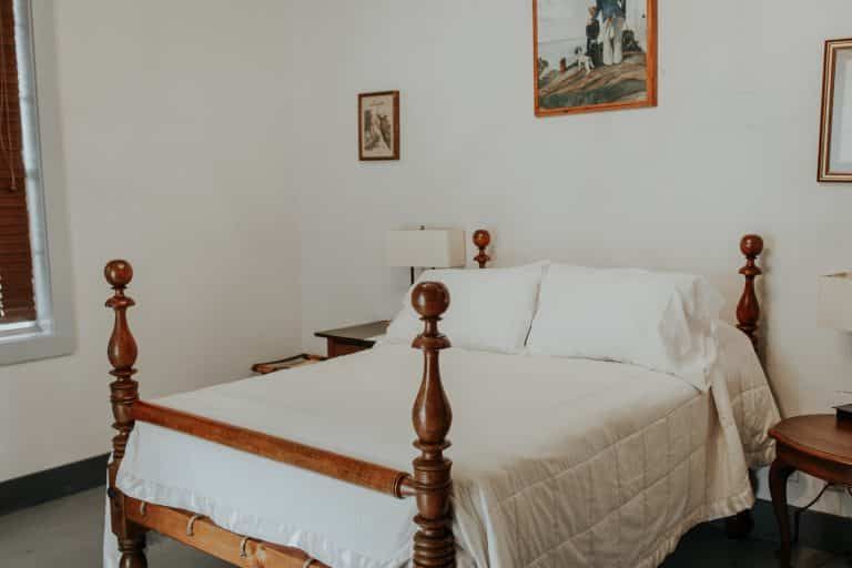 A bedroom with a bed , nightstand , lamp and a picture on the wall.