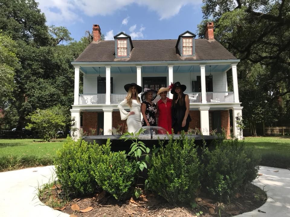 A group of women standing in front of a large white house