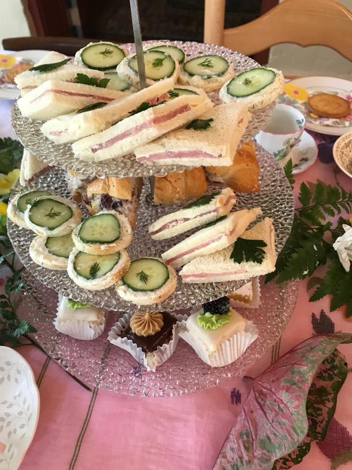 A glass plate topped with sandwiches and cucumbers on a table.