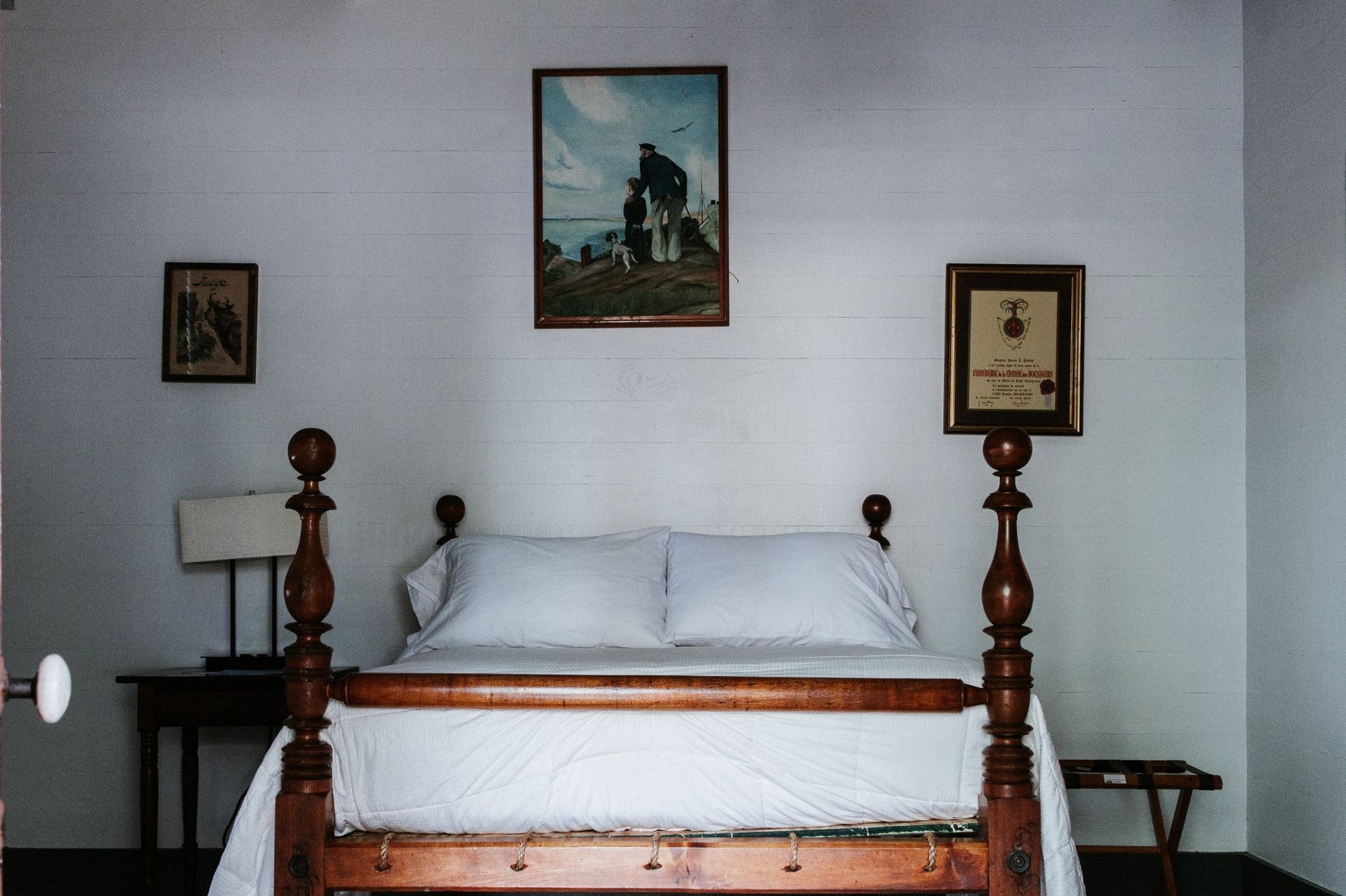 A bedroom with a bed and two pictures on the wall