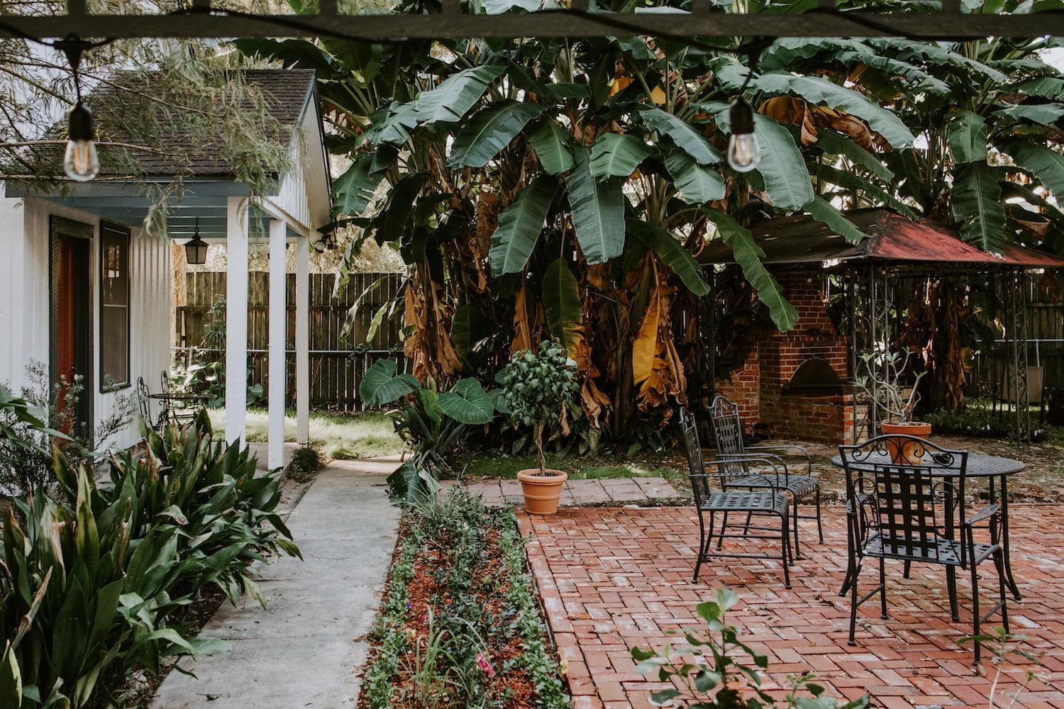 A brick patio with tables and chairs in front of a house.