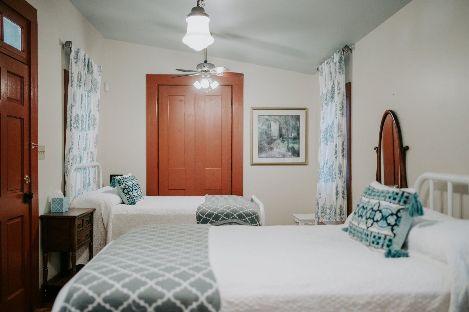 A bedroom with two beds and a ceiling fan.