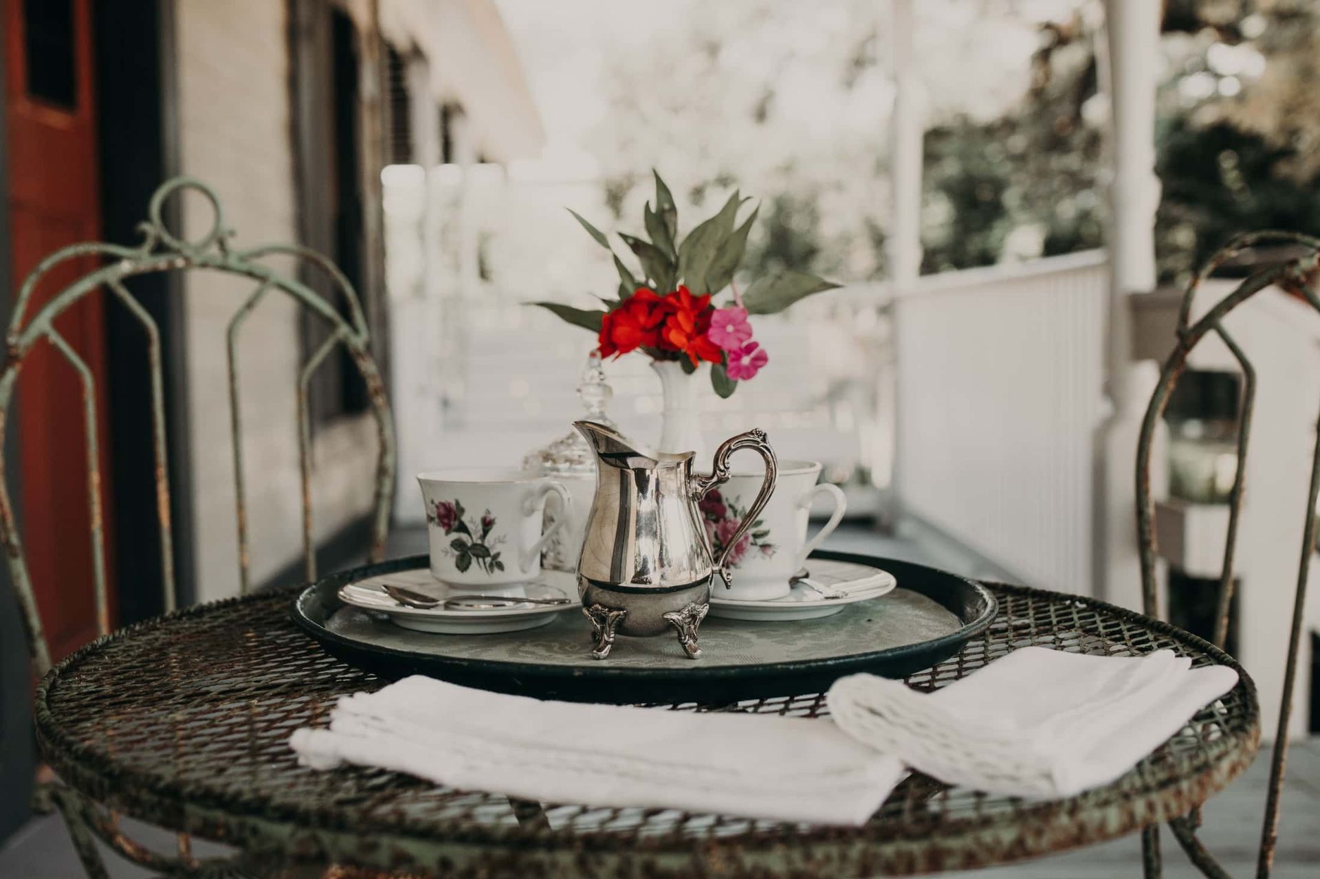 A table with a tea set and a vase of flowers on it.
