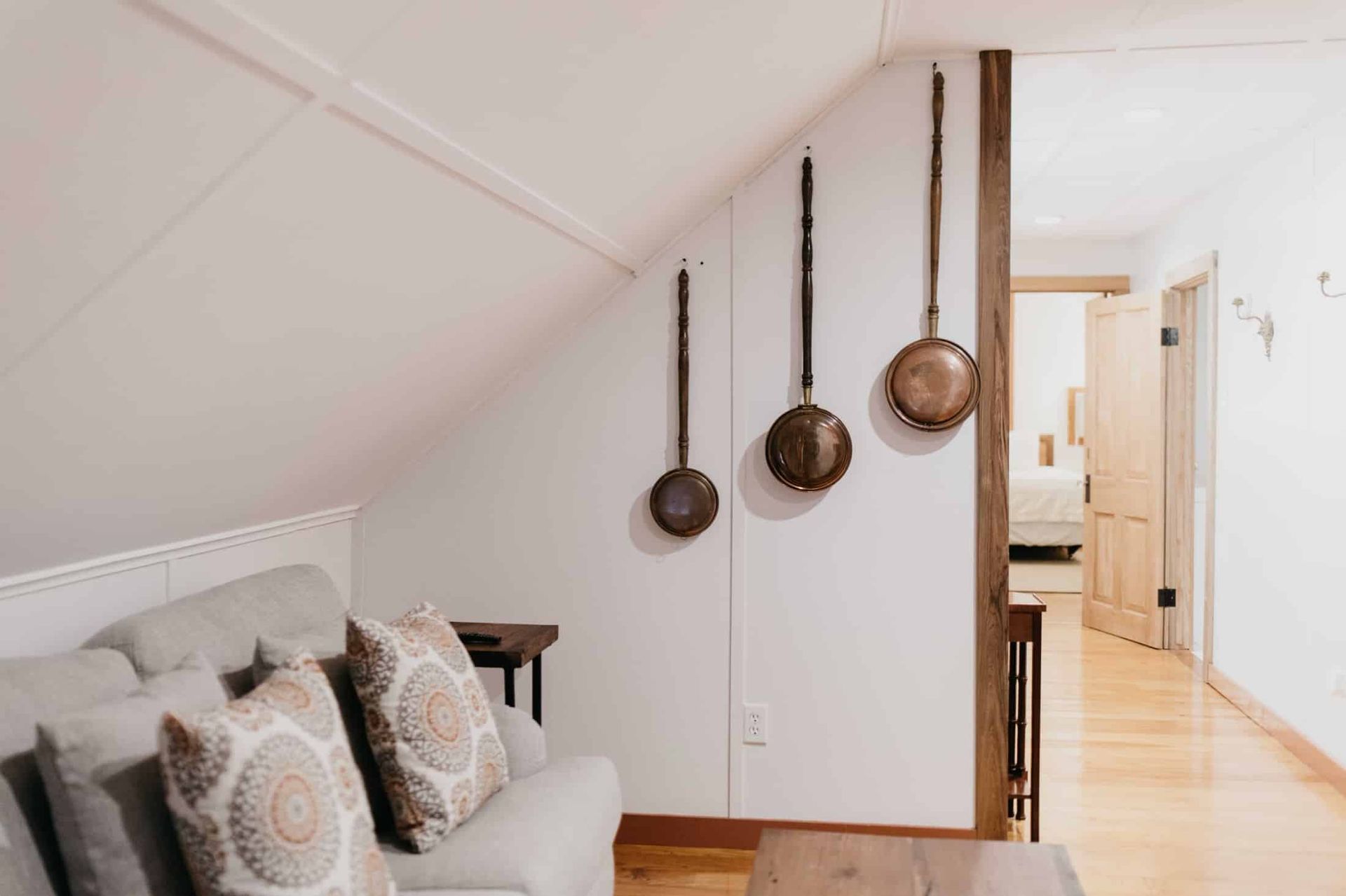 A living room with a couch and pots and pans hanging on the wall.