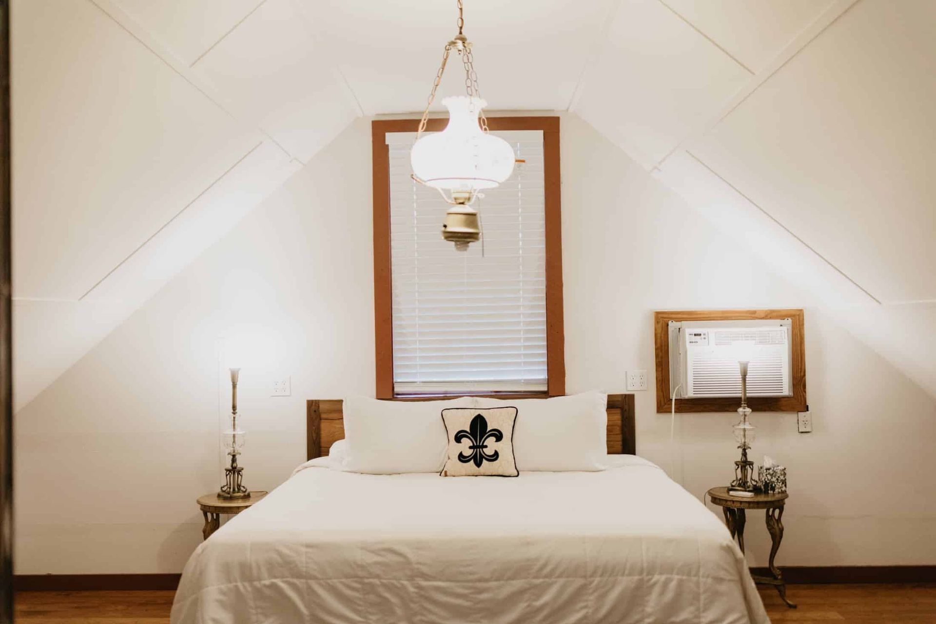 A bedroom with a bed , lamps , and a window.