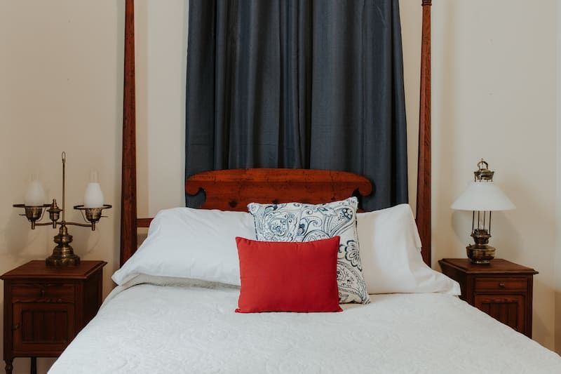A bed with a red pillow on top of it in a bedroom.
