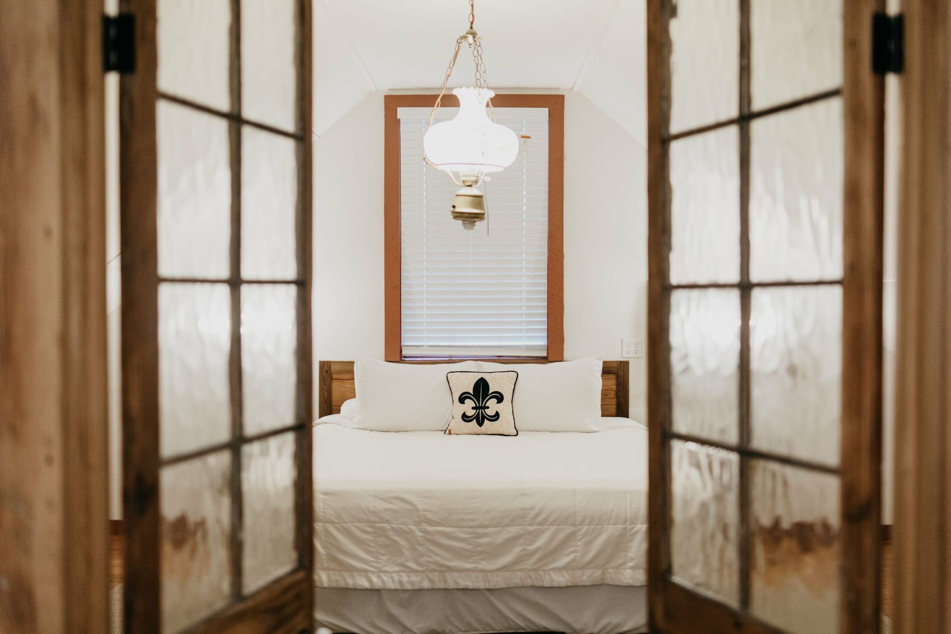A bedroom with a bed and a lamp hanging from the ceiling.
