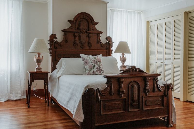 A bedroom with a wooden bed and two lamps.