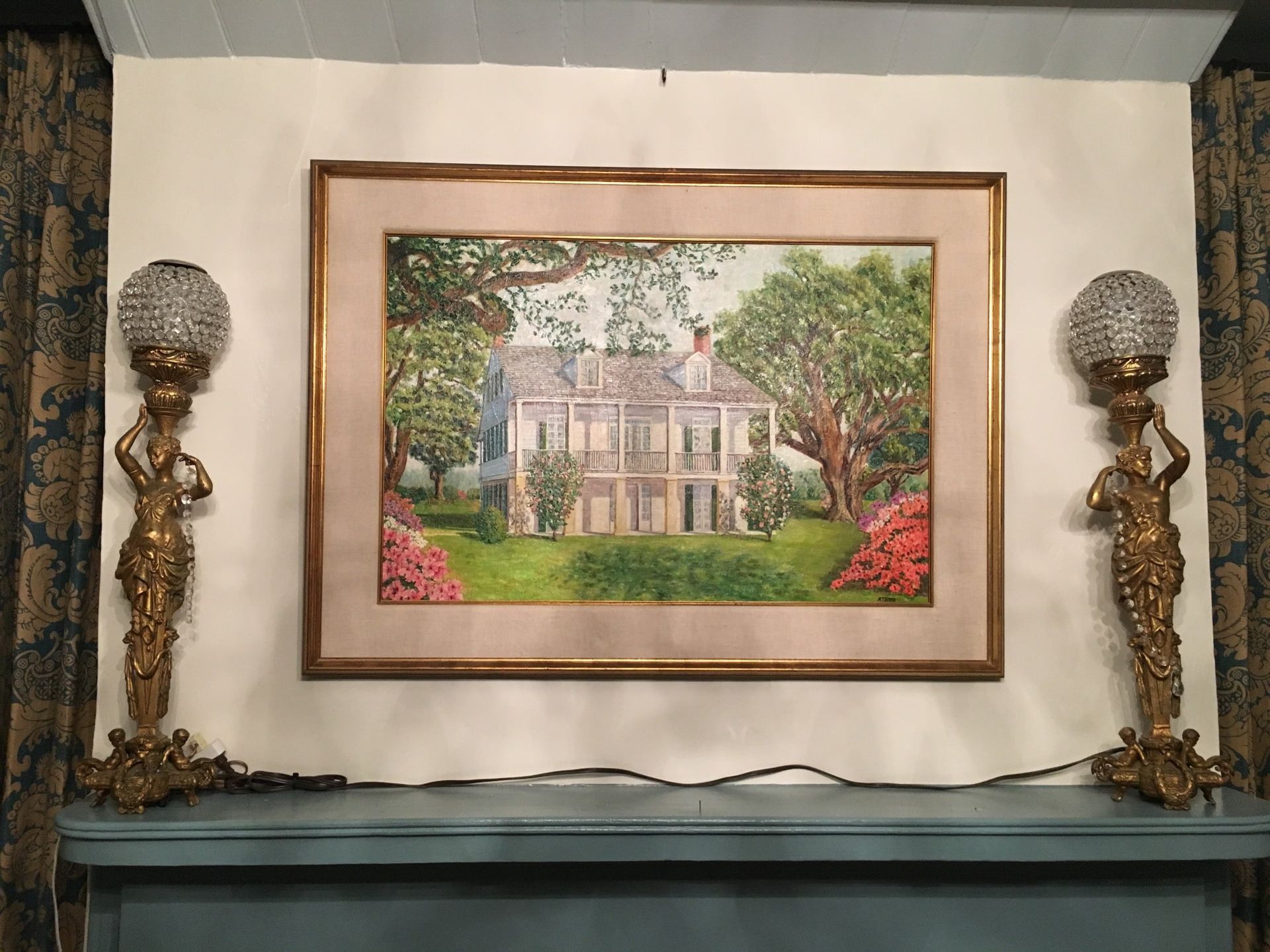 A painting of a house is hanging on a wall next to two lamps.