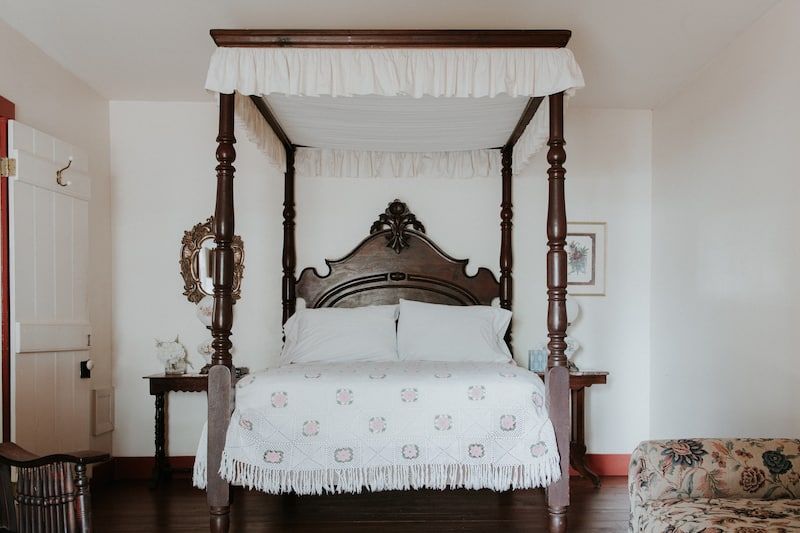 A bedroom with a four poster bed and a couch.
