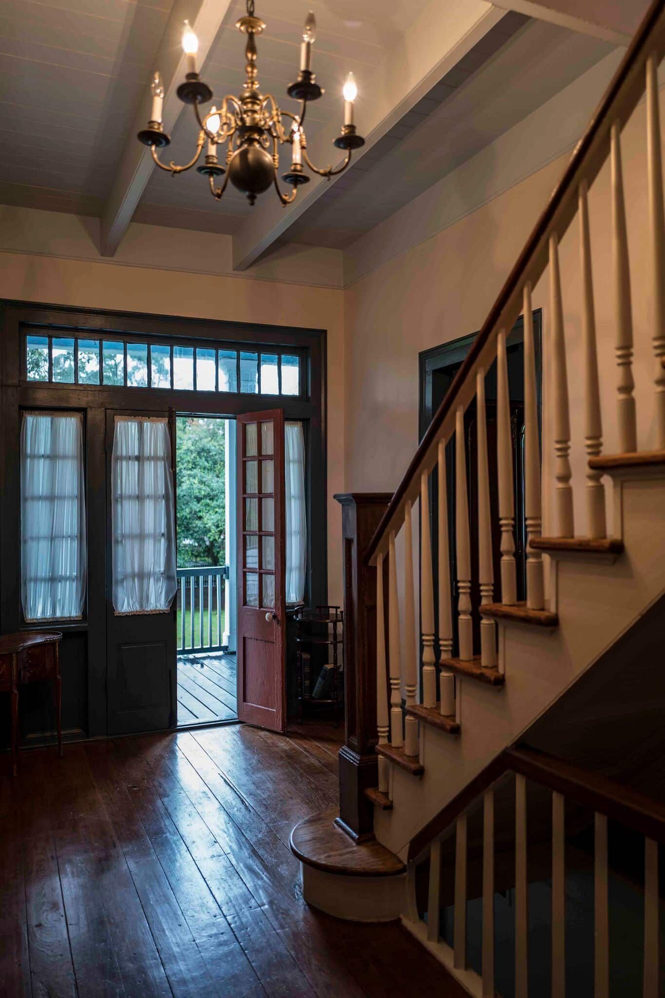 A hallway with stairs and a chandelier hanging from the ceiling.