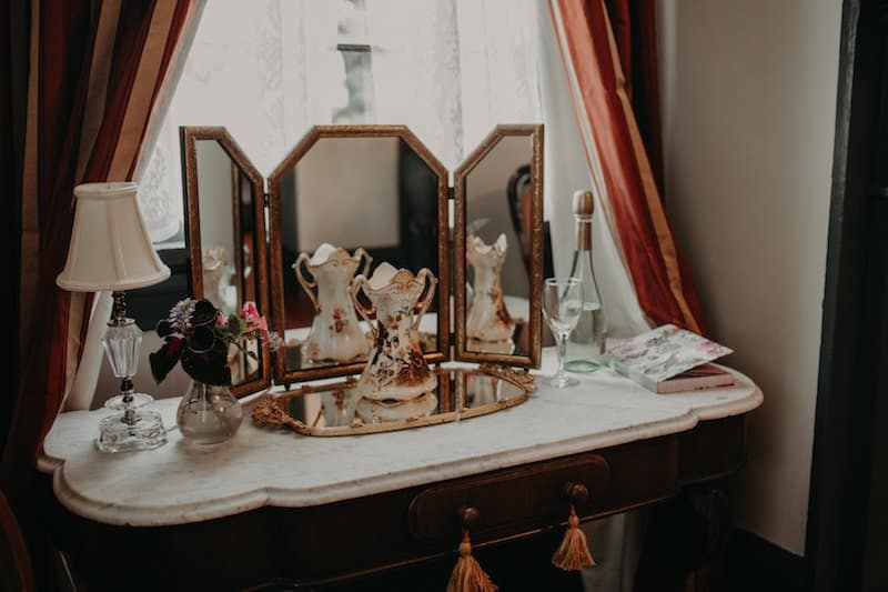 A dressing table with a mirror and a lamp on it.