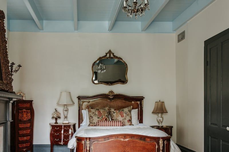 A bedroom with a bed , nightstand , mirror and chandelier.