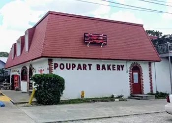 A white building with a red roof that says poupart bakery
