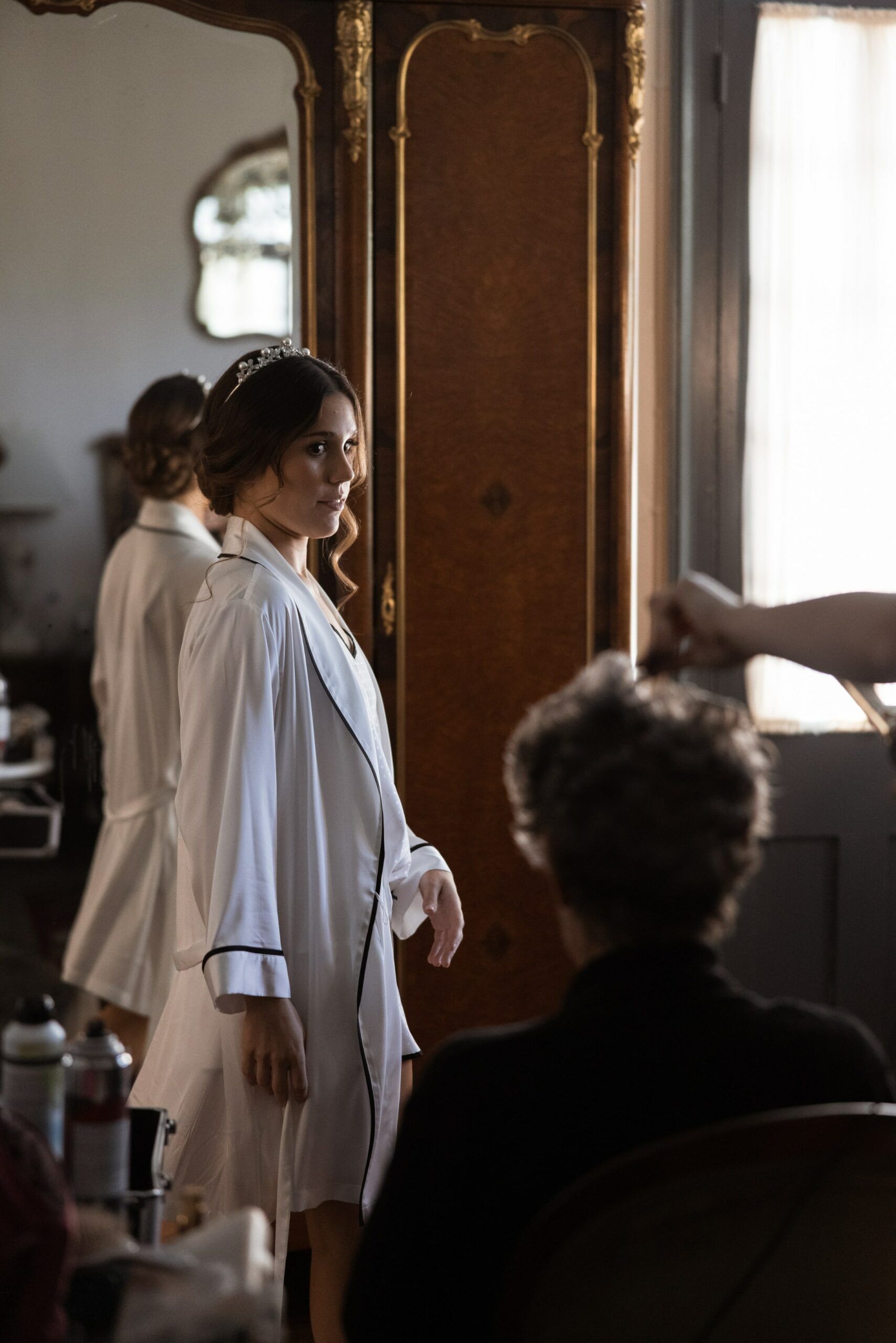 A woman in a white robe is standing in front of a mirror.