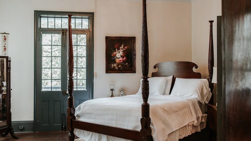 A bedroom with a four poster bed and a painting on the wall.