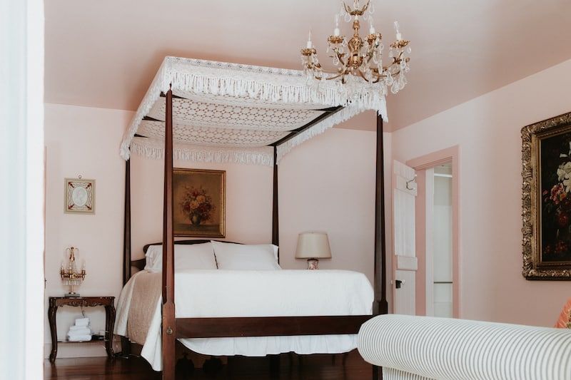 A bedroom with a four poster bed and a chandelier.