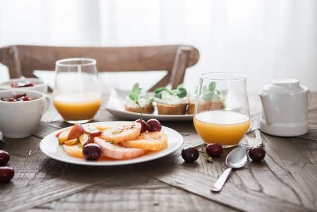 A wooden table topped with plates of food and glasses of orange juice.