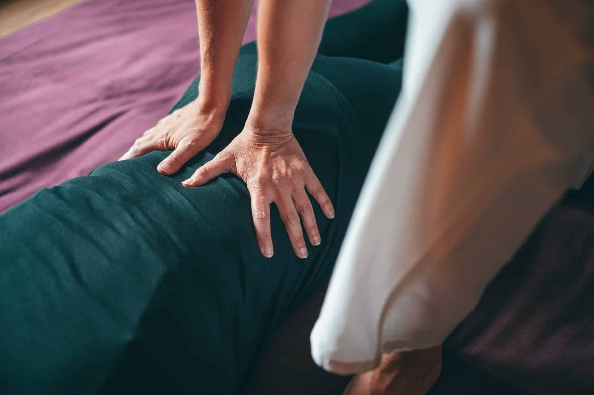 A woman is giving a massage to another woman on a bed.