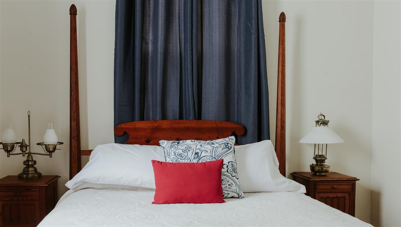A bedroom with a bed , nightstands , lamps and curtains.