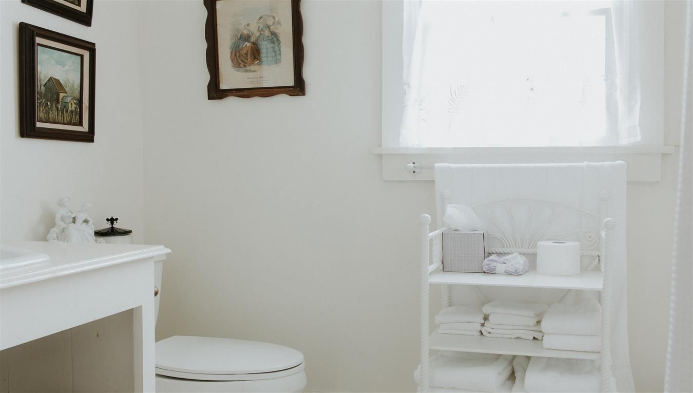 A bathroom with a toilet , sink , and window.