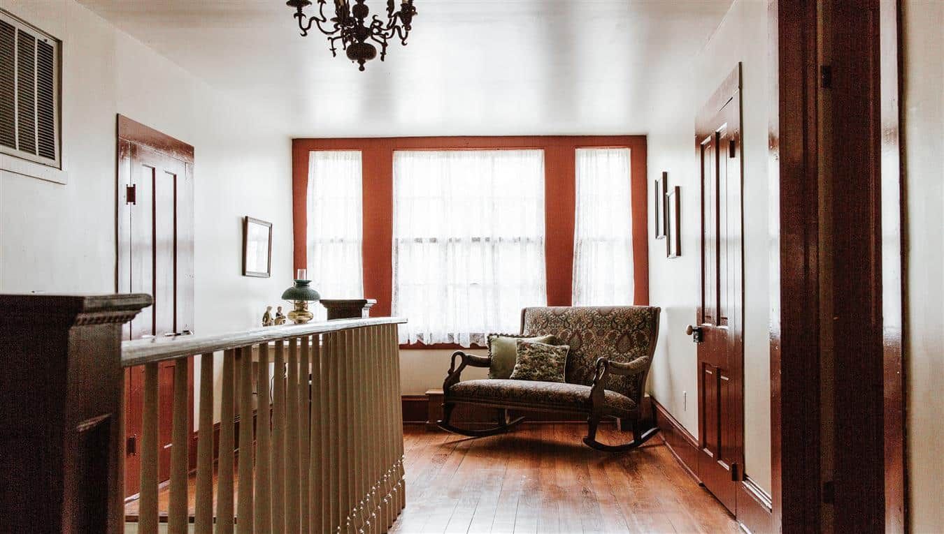 A hallway in a house with a rocking chair and a couch.