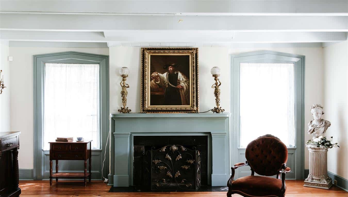 A living room with a fireplace and a painting on the mantle.