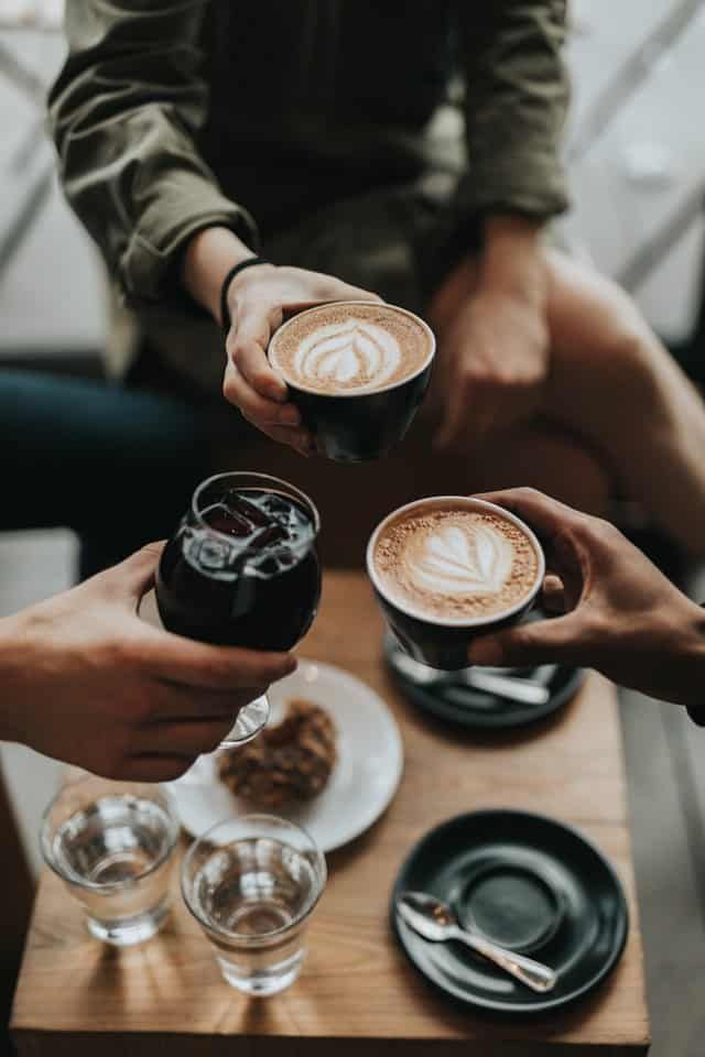 A group of people are sitting at a table holding cups of coffee.