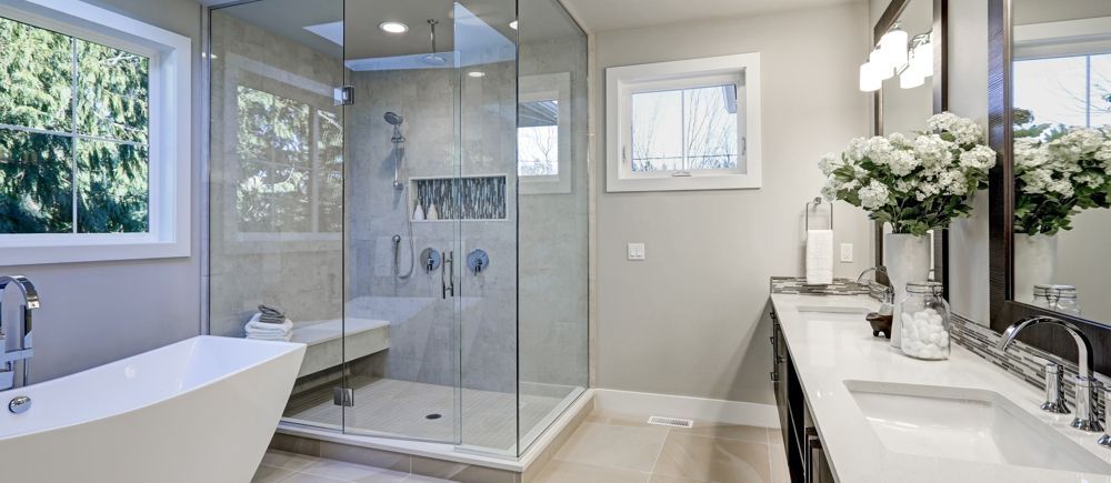 Modern bathroom with glass shower, soaking tub, double vanity with flowers.