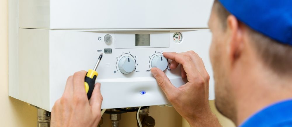 A person adjusts knobs on a white appliance with a screwdriver.
