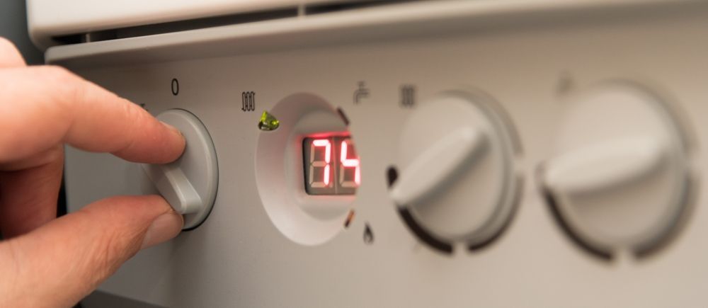 Person's hand turning a dial on a white appliance. A red digital display shows