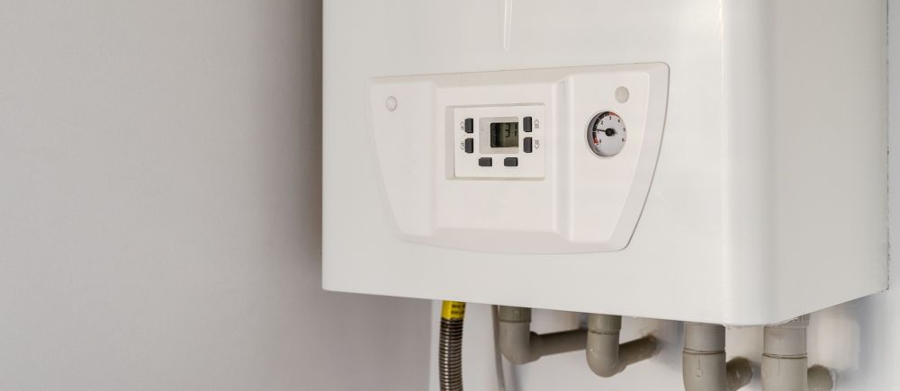 White wall-mounted gas boiler with display and pipes.