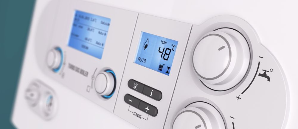 Close-up of a white boiler control panel with two blue digital displays and several knobs.