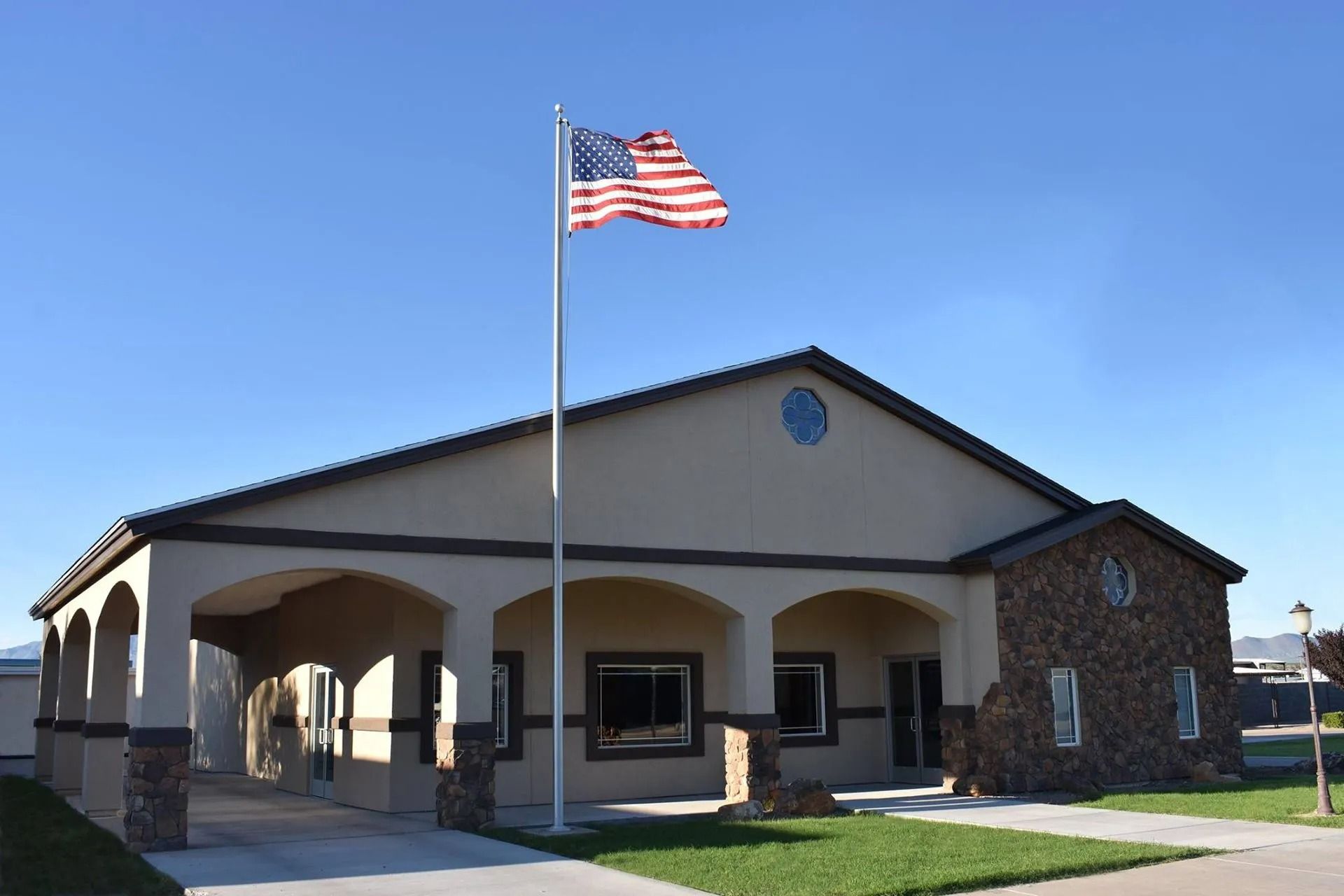 Single-story building with arched entrance and American flag on a pole in front.