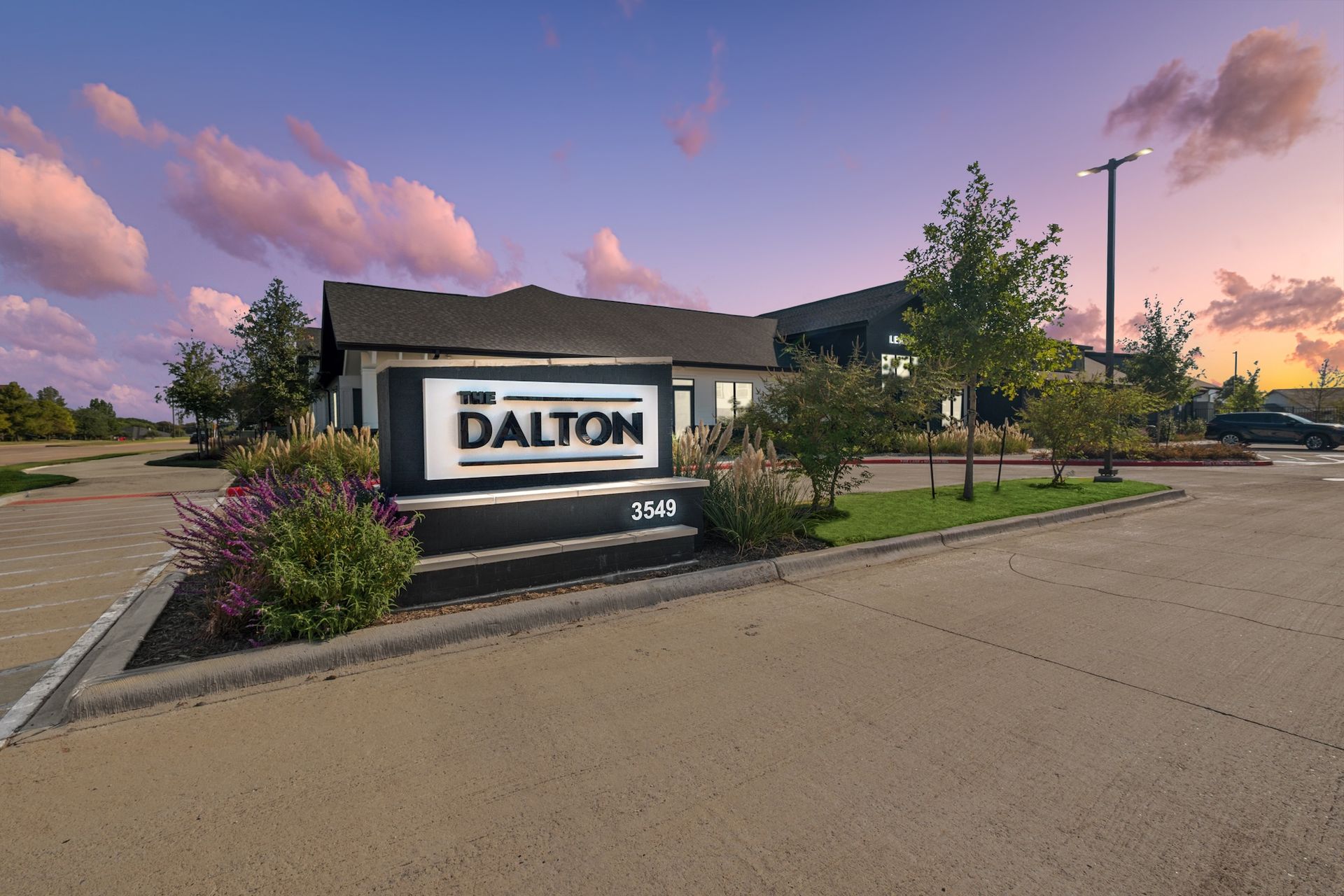 Sign for The Dalton apartments, a low-rise building, set at dusk under a colorful sky.