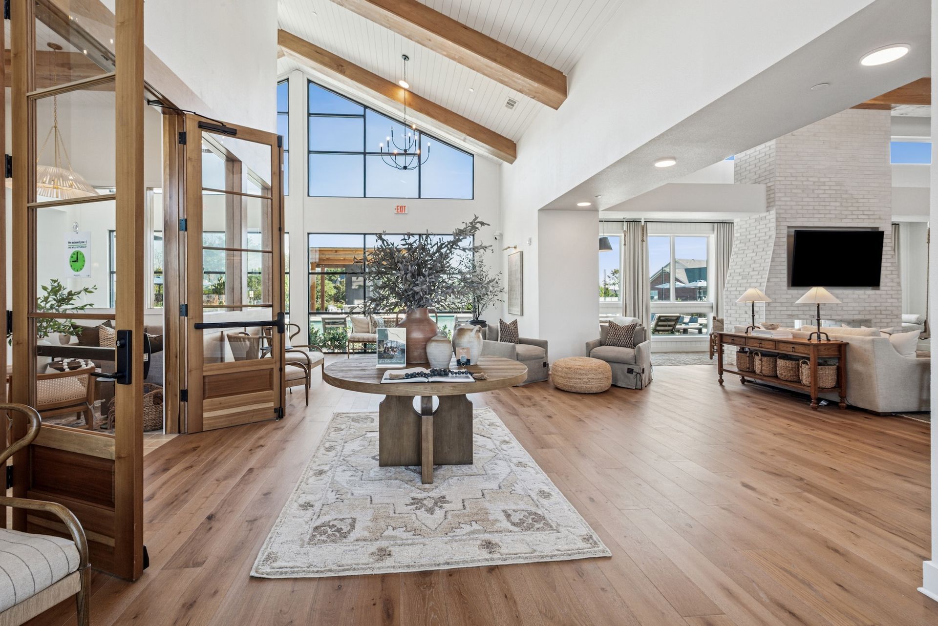 Spacious lobby with wood floors, high ceilings, large windows, and seating areas.