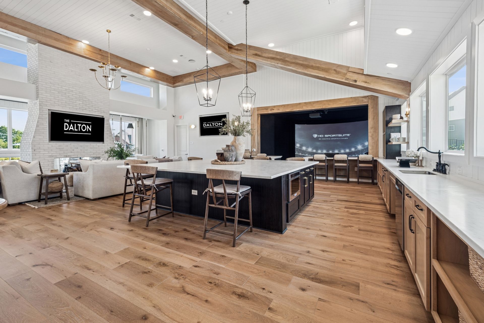 Spacious modern kitchen with island, seating, and entertainment area with exposed beams, light wood floors.