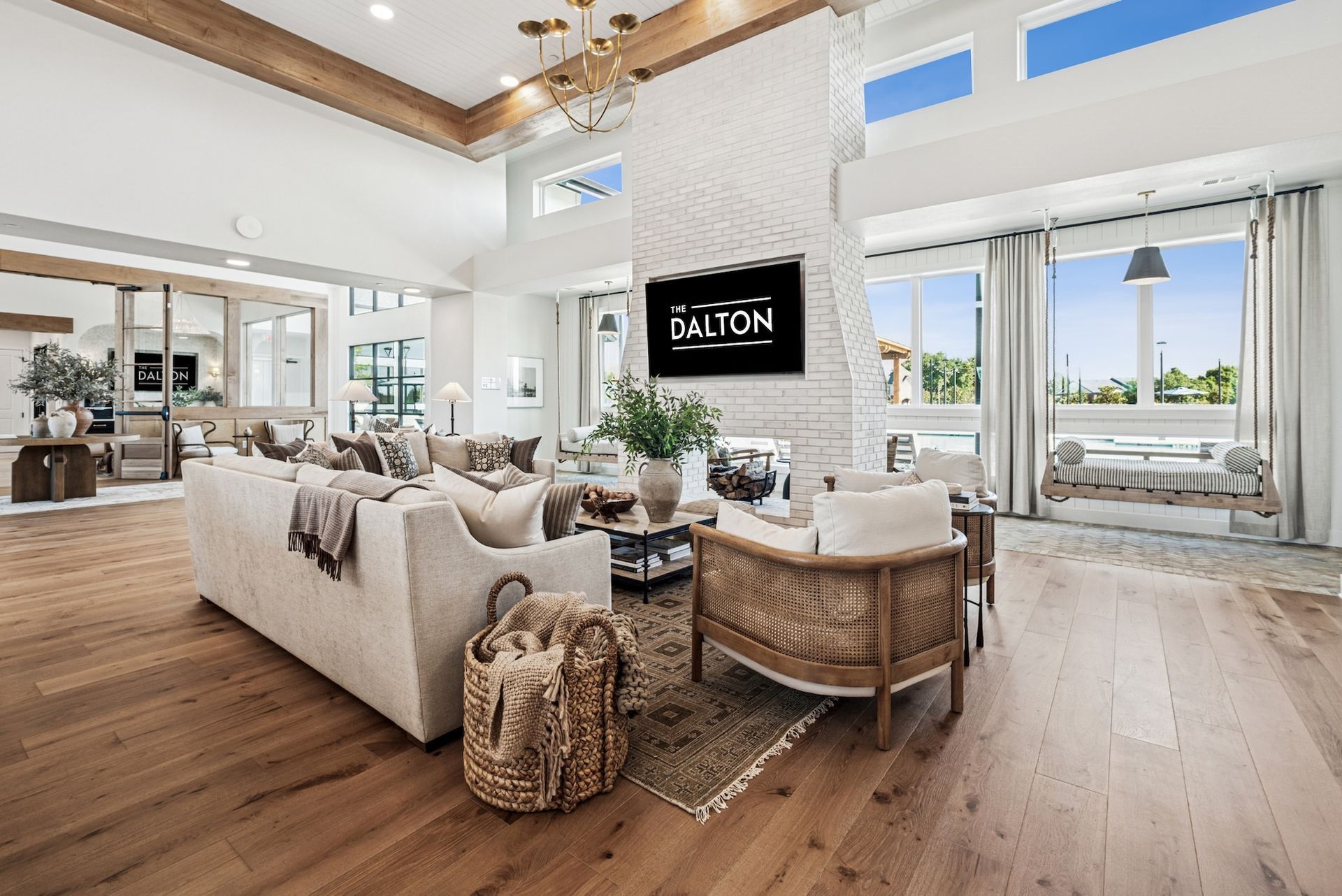 Spacious living room with hardwood floors, white walls, and a fireplace, with large windows and a sofa.