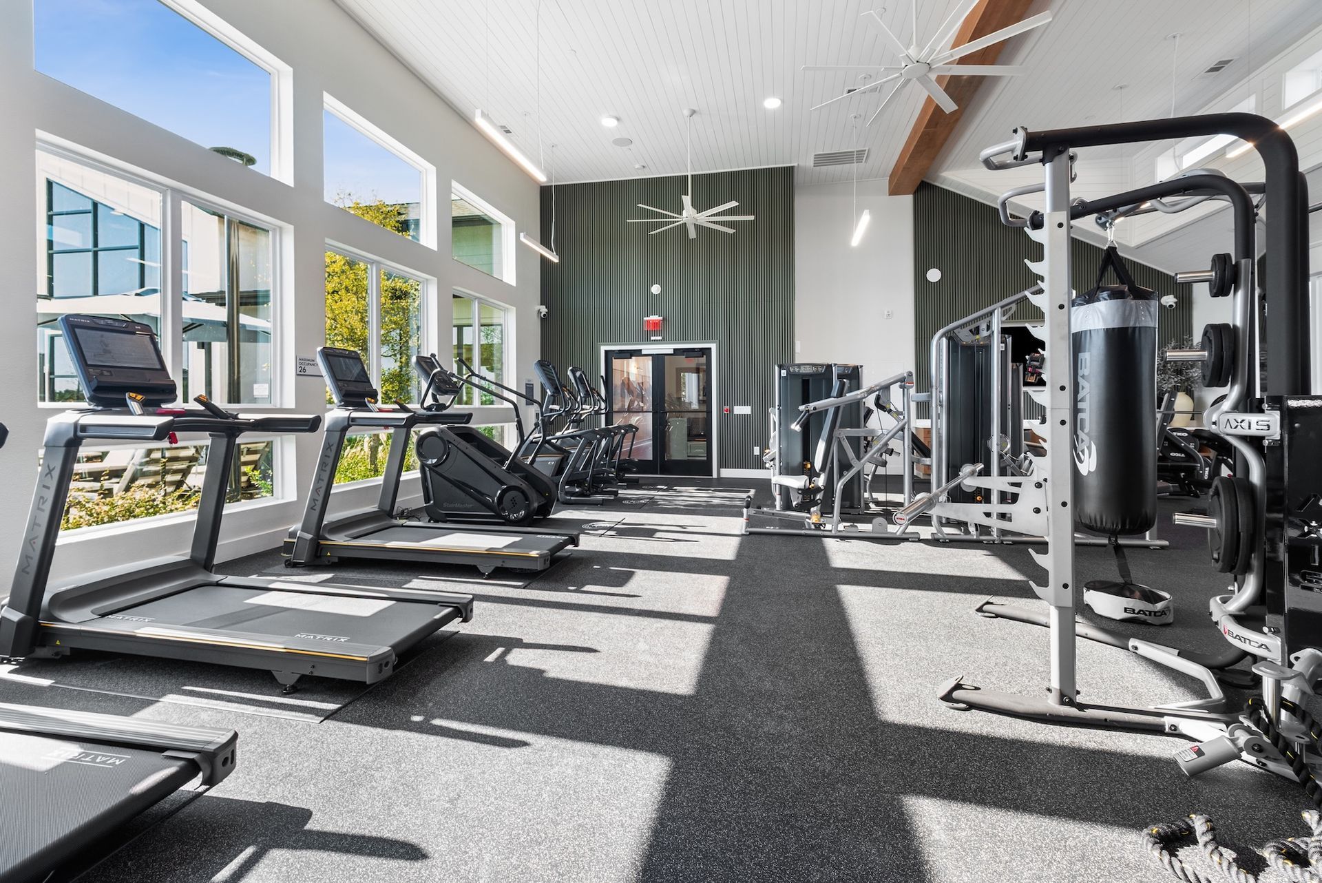 Gym interior with treadmills, weight machines, and large windows.