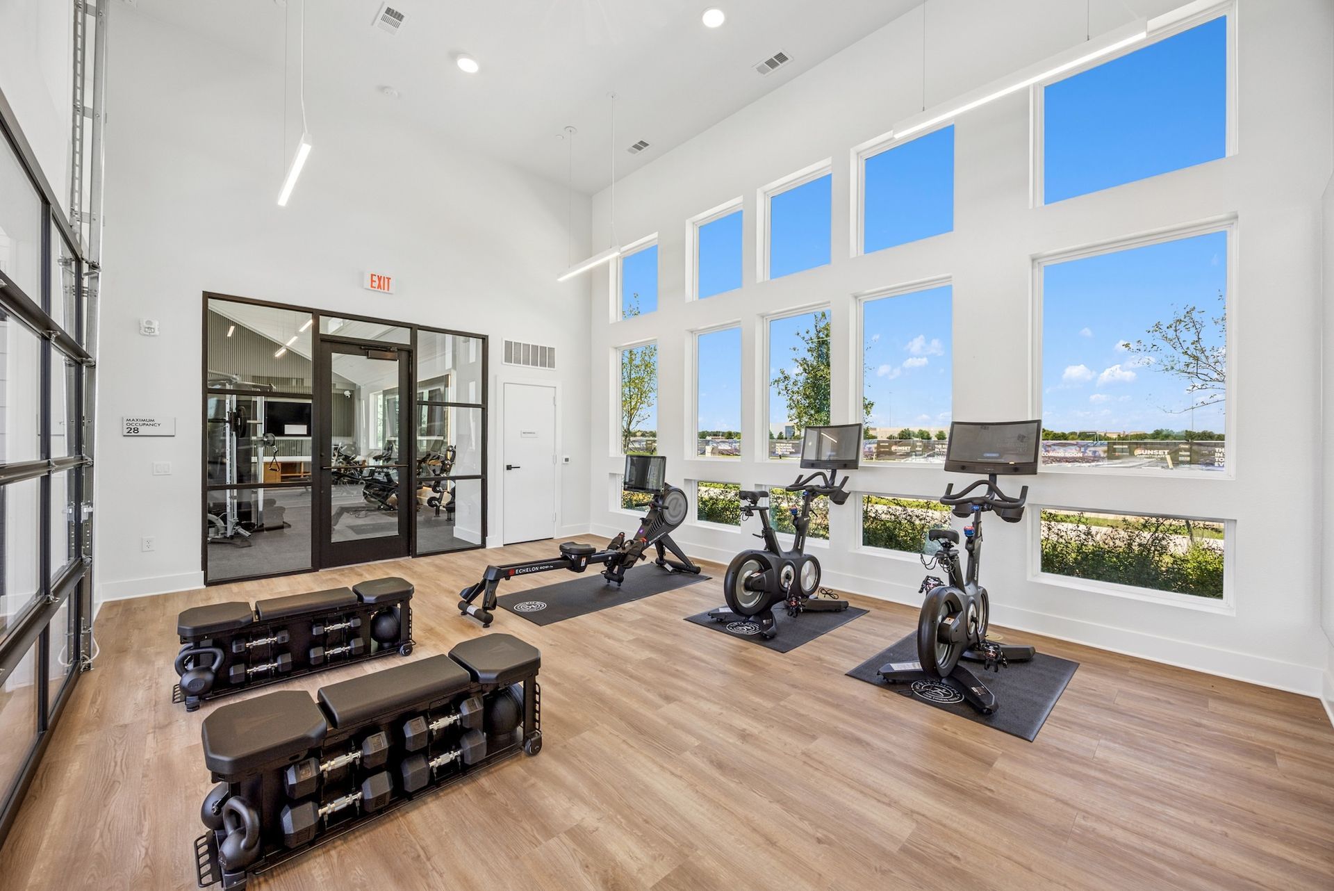 A gym with a lot of windows and exercise bikes.