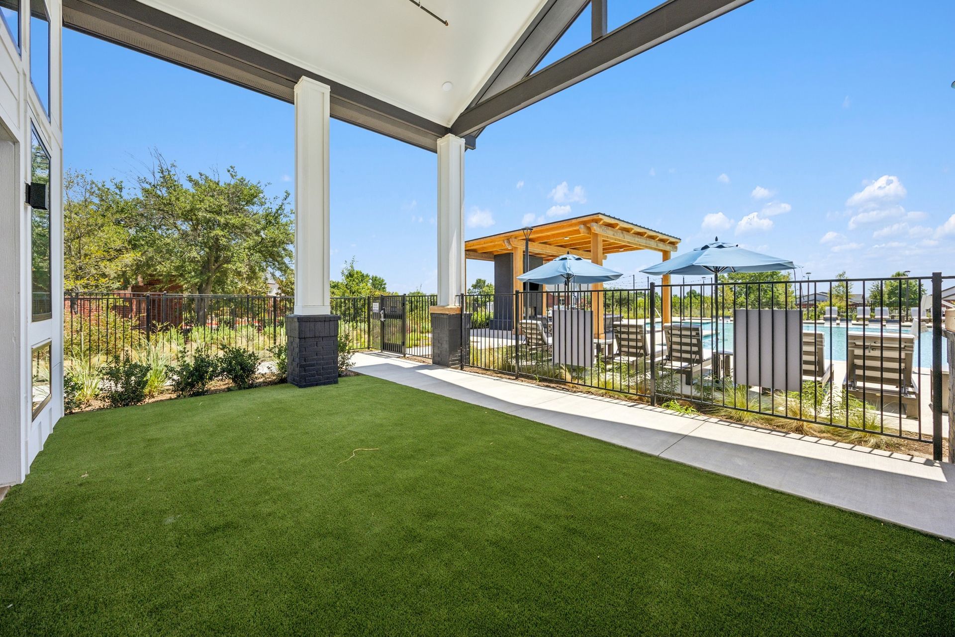 A large lawn with a pergola and a pool in the background.