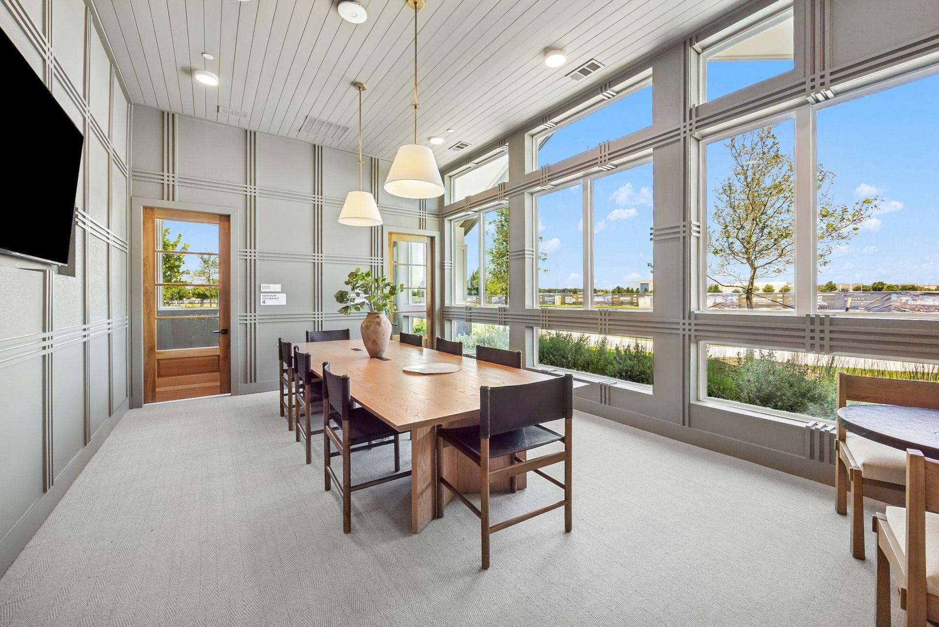 A conference room with a long table and chairs and a flat screen tv.