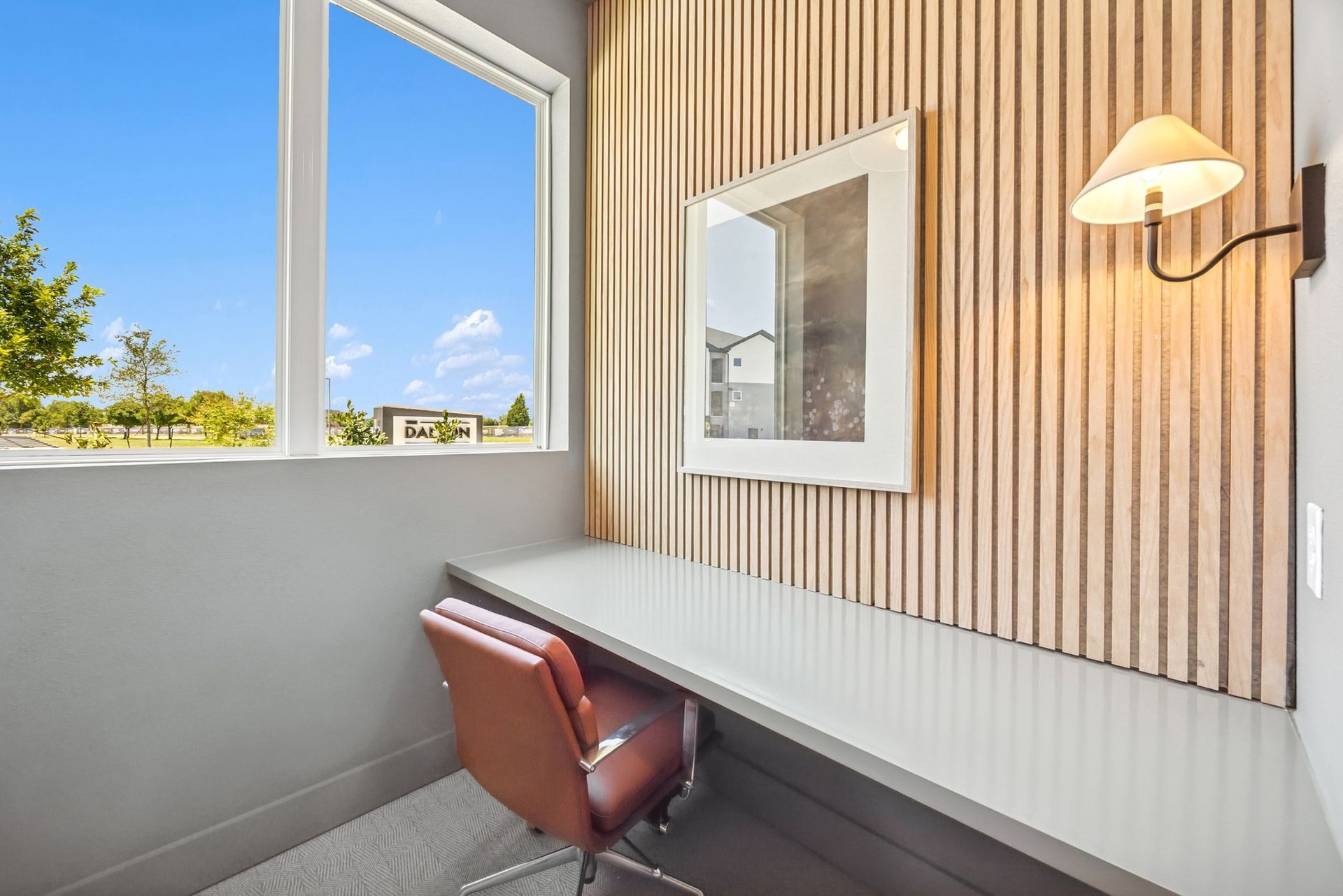A room with a desk and chair in front of a window.