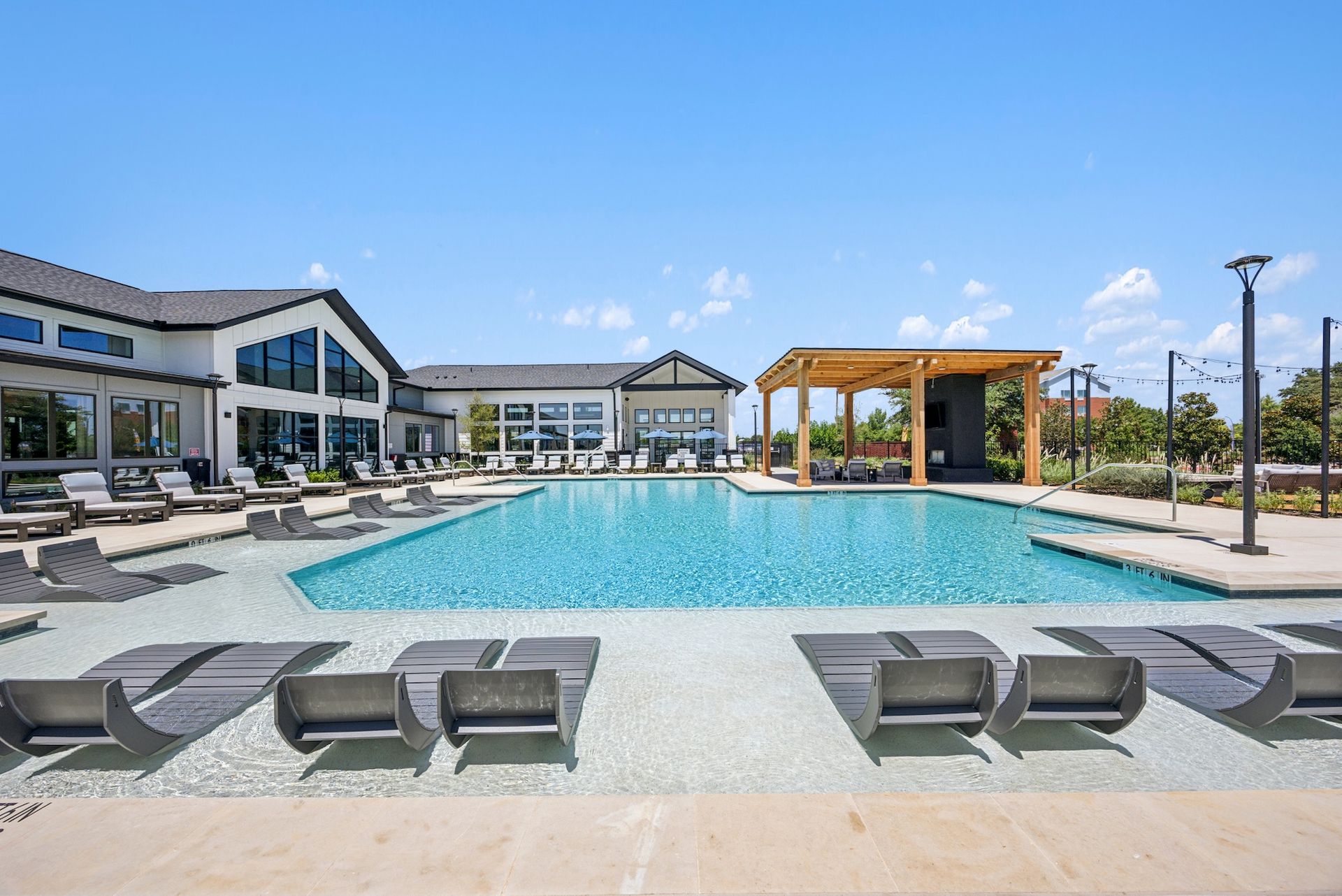 A large swimming pool surrounded by chairs and a building.