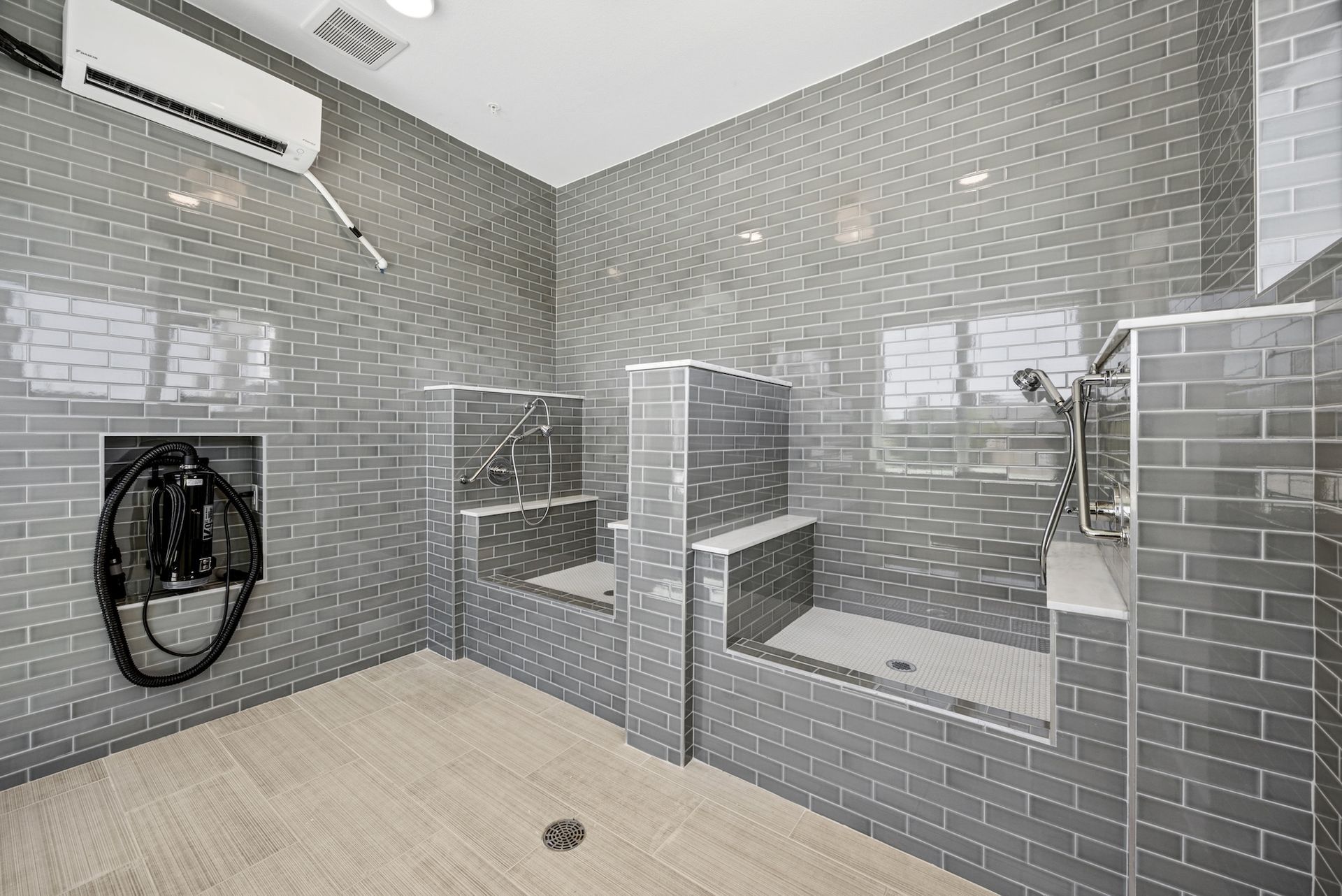 A bathroom with gray tile walls and a shower.