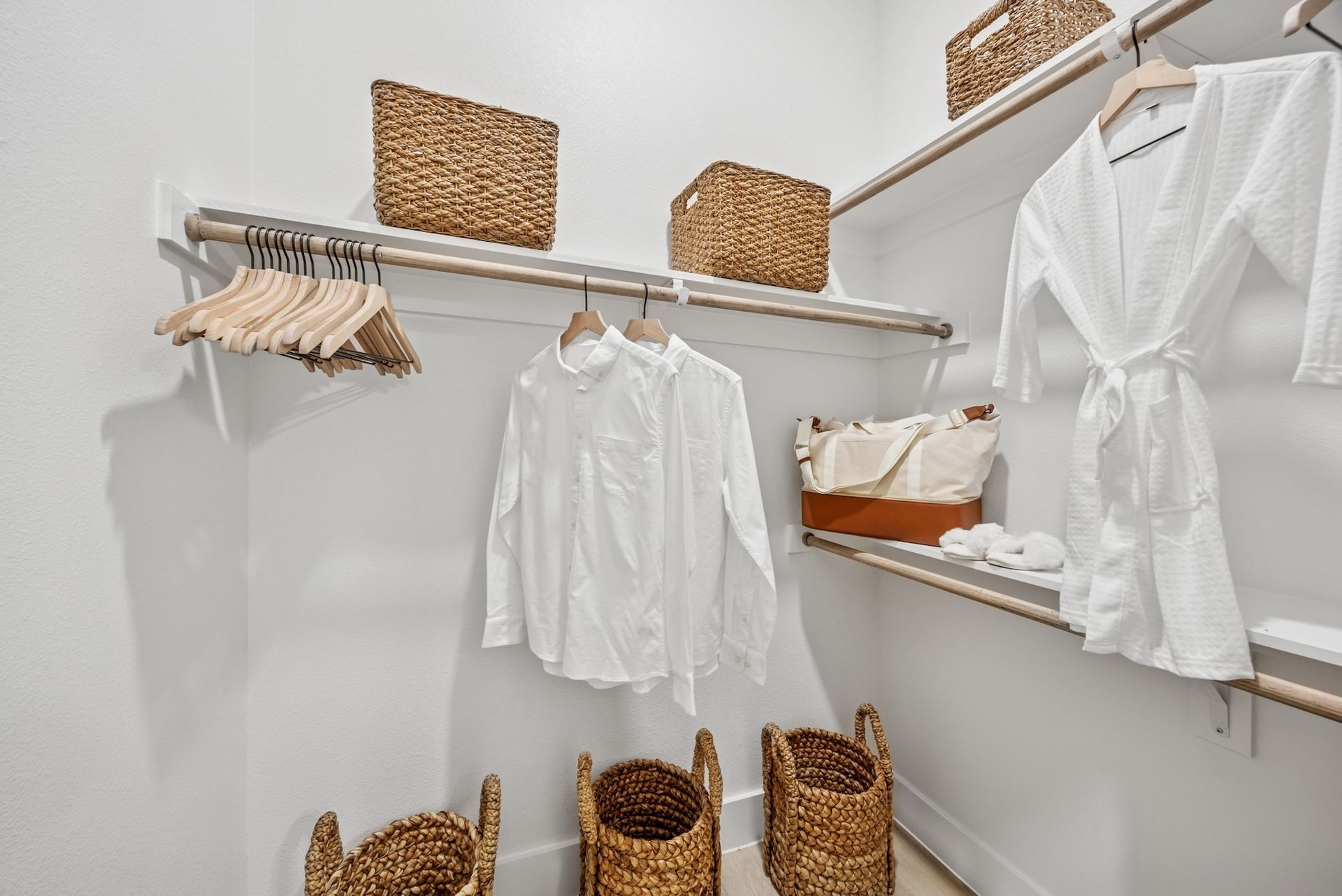A walk in closet with clothes hanging on racks and baskets.