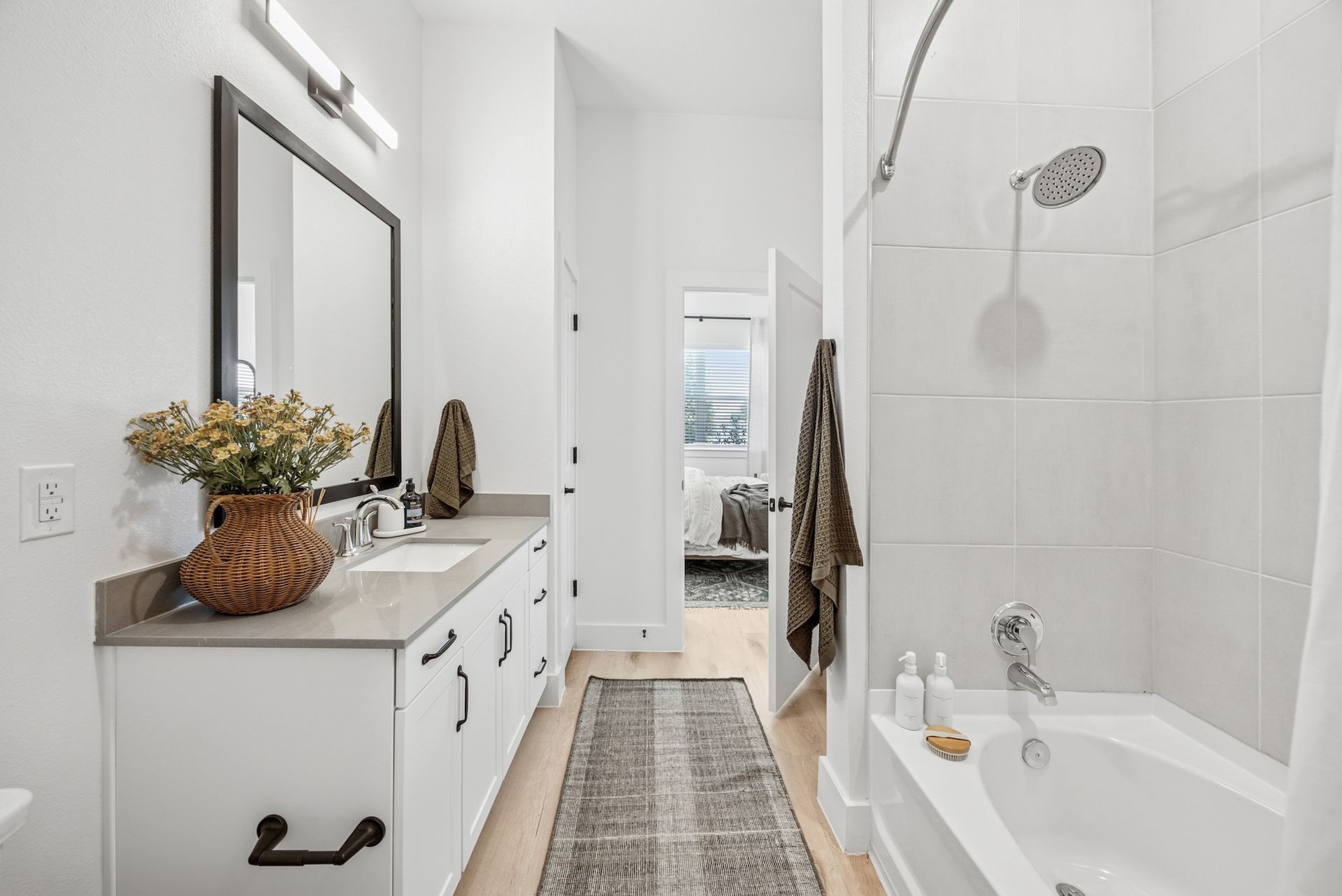 A bathroom with a tub , sink , mirror and shower.